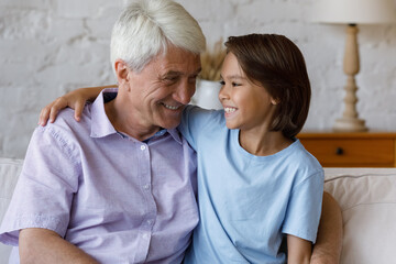 Happy grandson boy talking to loving grandpa, enjoying trusting friendship. Grandkid embracing...