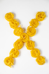 few homemade fettuccine nest in the shape of the letter X isolated on white background