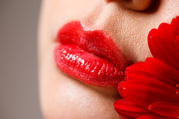 Sexy full female lips with red lipstick on the background of a flower. Aesthetic medicine services...