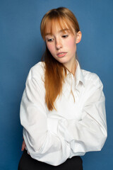 Bright young girl with red hair and white skin isolated on blue in blouse