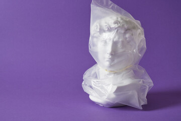 head of david in a transparent plastic bag on a purple background copy space