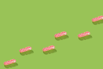 Pink heart shape glitter in a medicine pill on a green background. Valentine day pattern. Social broken heart pain cure in tablets. Love concept. Creative minimal idea of break up disease.