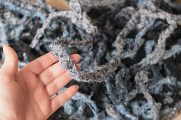 hand holds yarn with pigtails from old jeans, denim yarn for knitting carpet and other decor, scandi or boho style