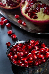 Fresh Pomegranate placed in old silver cup full of seeds in backlit with dark and moody tone