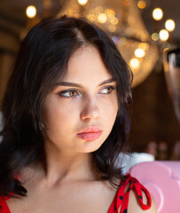 Fototapeta premium Portrait of young dark haired woman with white skin with lights behind with plump lips