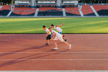 Fototapeta premium A large group of boys ' children are taught by a coach at the start before running at the stadium during sunset. A healthy lifestyle.