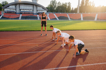 A group of boys ' children are taught by a coach at the start before running at the stadium during...