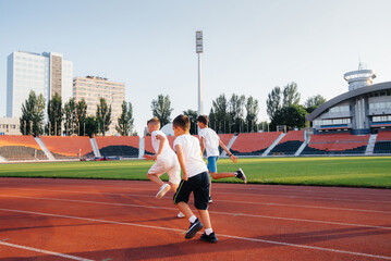 Obraz premium A large group of boys ' children are taught by a coach at the start before running at the stadium during sunset. A healthy lifestyle.