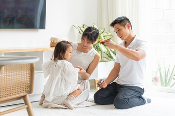 Obraz na płótnie Canvas Familia asiática jugando con su hija con juguetes en la sala de su hogar