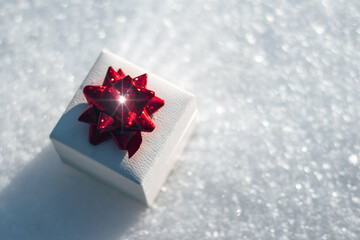 white box with red bow on the background of snow with radiance inside, space for text, Valentine's...
