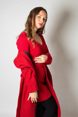 Fototapeta premium Attractive young european woman in red coat isolated on light grey