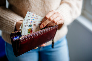 Woman putting Pounds in wallet - obrazy, fototapety, plakaty