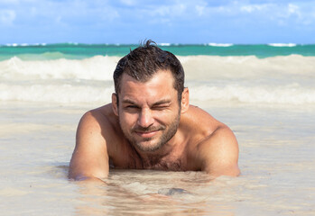 Adult man lying down on sand on the beach against the beautiful sea. Beach holiday, vacation concept.