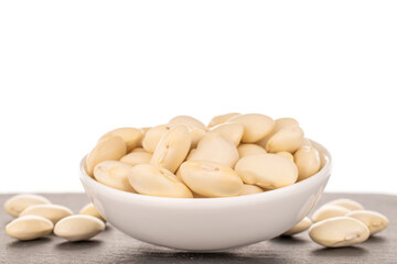 Lots of organic white beans in a white saucer, close-up, isolated on white.