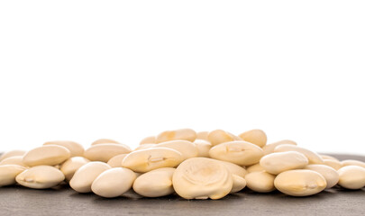 Lots of organic white beans on a slate stone, close-up isolated on white.