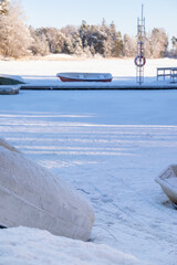 View of abandoned row boats on the shore with winter sun illuminating the background.