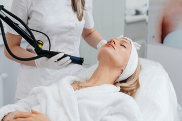 A young girl gets a carbon peeling for the skin of the neck in a beauty salon. Laser pulses cleanse the skin. Hardware cosmetology. The process of photothermolysis, warming the skin.