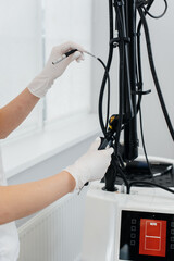 The cosmetologist's hand adjusts a modern laser in a beauty salon close-up. Laser pulses cleanse the skin. Hardware cosmetology. The process of photothermolysis, warming the skin.