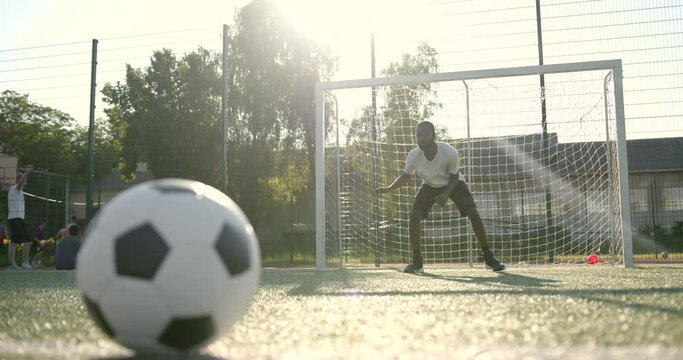 Closeup of ball on the field while man standing at soccer net