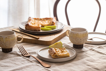 Homemade apple pie and apple pie slices, coffee cups on the terrace table at the morning. Breakfast table setting