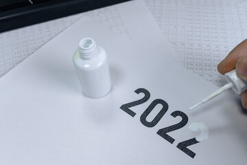 A man erases the year 2022 with correction fluid. The concept of the outgoing 2022