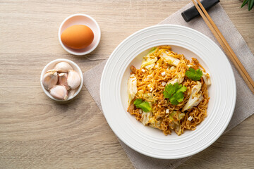 Stir fried instant noodle with canned mackerel fish,Cabbage and egg in white plate.Top view