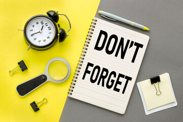 don't forget. yellow office stationery with magnifier and alarm clock on gray background.