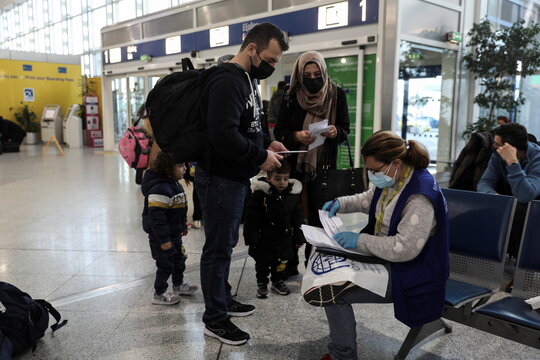 An IOM official checks the papers of an Afghan family before their flight, after being granted visas by Australia, at the Eleftherios Venizelos International Airport in Athens