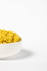 Raw Cavatappi Cellentani pasta in a plate isolated on yellow background