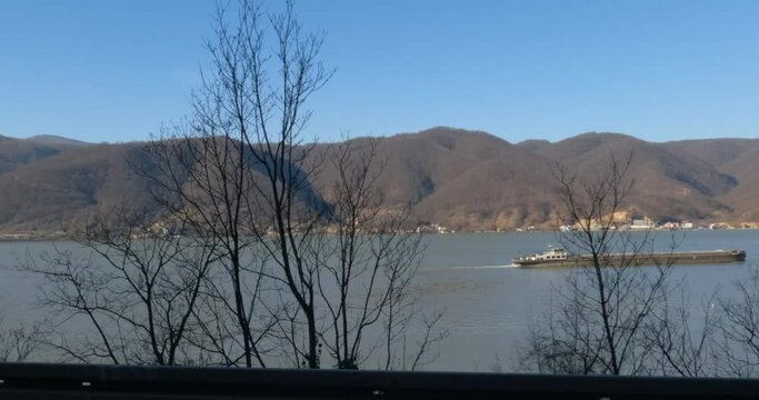 River tugboat on Danube river , nature landscape. View from car during drive at road on riverbank.