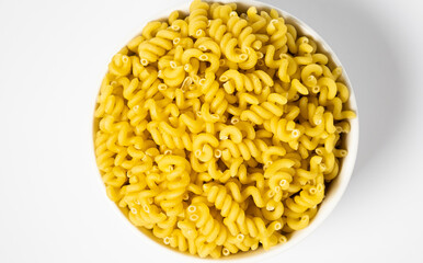 Raw Cavatappi Cellentani pasta in a plate isolated on yellow background top view