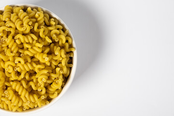 Raw Cavatappi Cellentani pasta in a plate isolated on yellow background top view