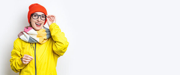 Cheerful young girl in glasses, in a yellow jacket on a light background. Banner.