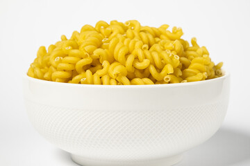 Raw Cavatappi Cellentani pasta in a plate isolated on yellow background