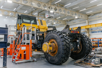 A disassembled dump truck is being repaired in the garage.	
