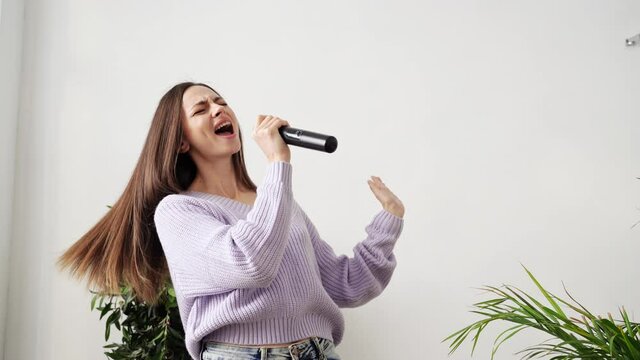 Young woman sing at home. Karaoke black microphone. House lyrics dance. Funny song. Independent home lifestyle. Sitting quarantine action. Purple dress