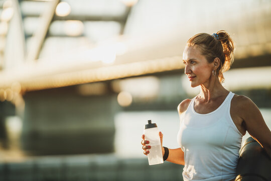 Woman With Water Bottle Resting After Training Near The River
