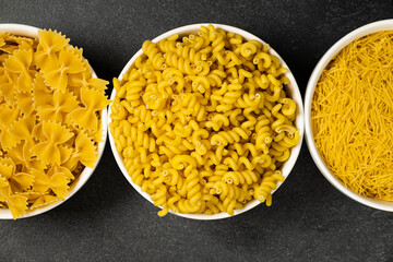 Close up of several types of dry pasta in a plate on dark background