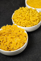 Close up of several types of dry pasta in a plate on dark background