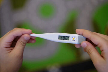 Close-up of thermometer. Child measures his temperature. Sick kid with high fever.