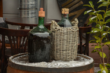 Large Vintage Wine Bottles in wicker basket on a barrel