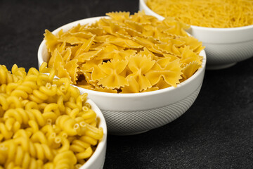 Close up of several types of dry pasta in a plate on dark background