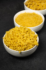 Close up of several types of dry pasta in a plate on dark background