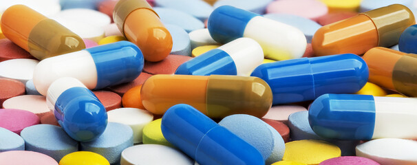 Heap of medical pills in white, blue and other colors.  Concept of healthcare and medicine.