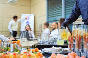 A young waiter pours drinks for catering.