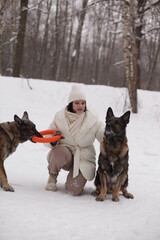 a girl in a white jacket playing with dogs