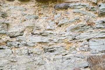 Fragment of ancient medieval fortress wall made of limestone. Vintage background. Natural old stone. Pattern in medieval style. Elements of medieval architecture. Selective focus.