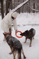 a girl in a white jacket playing with dogs