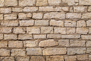 Fragment of ancient medieval fortress wall made of limestone. Vintage background. Natural old stone. Pattern in medieval style. Elements of medieval architecture. Selective focus.