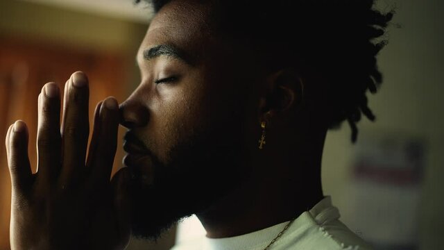 A spiritual black man praying with hands together